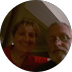 Two people, slightly out of focus, smiling in a room. One with glasses and a beard.