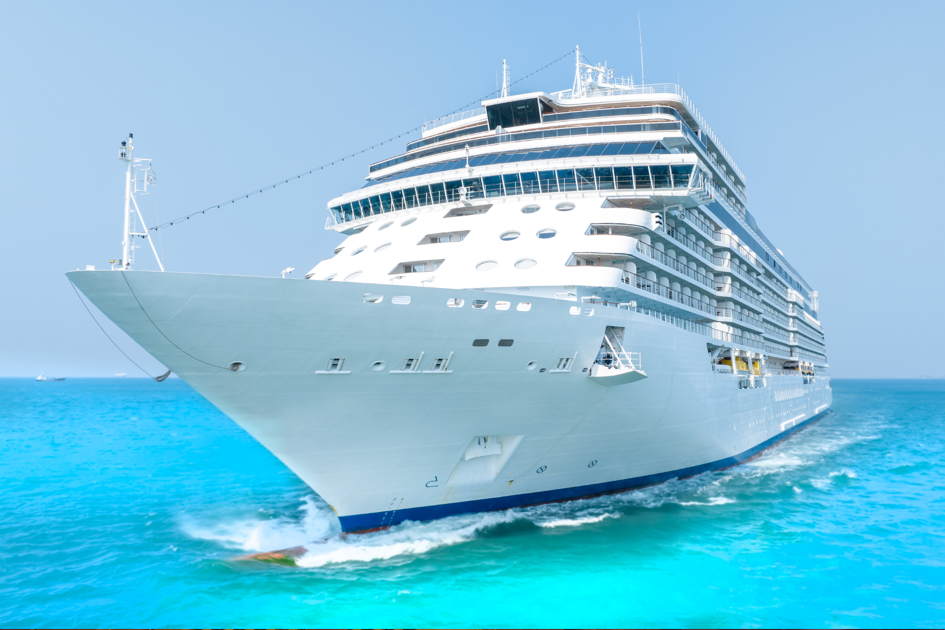 Large white cruise ship sailing on bright turquoise water under a clear blue sky