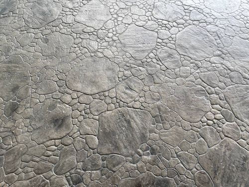 Close-up of cracked, dry gray ground with a rough, textured surface