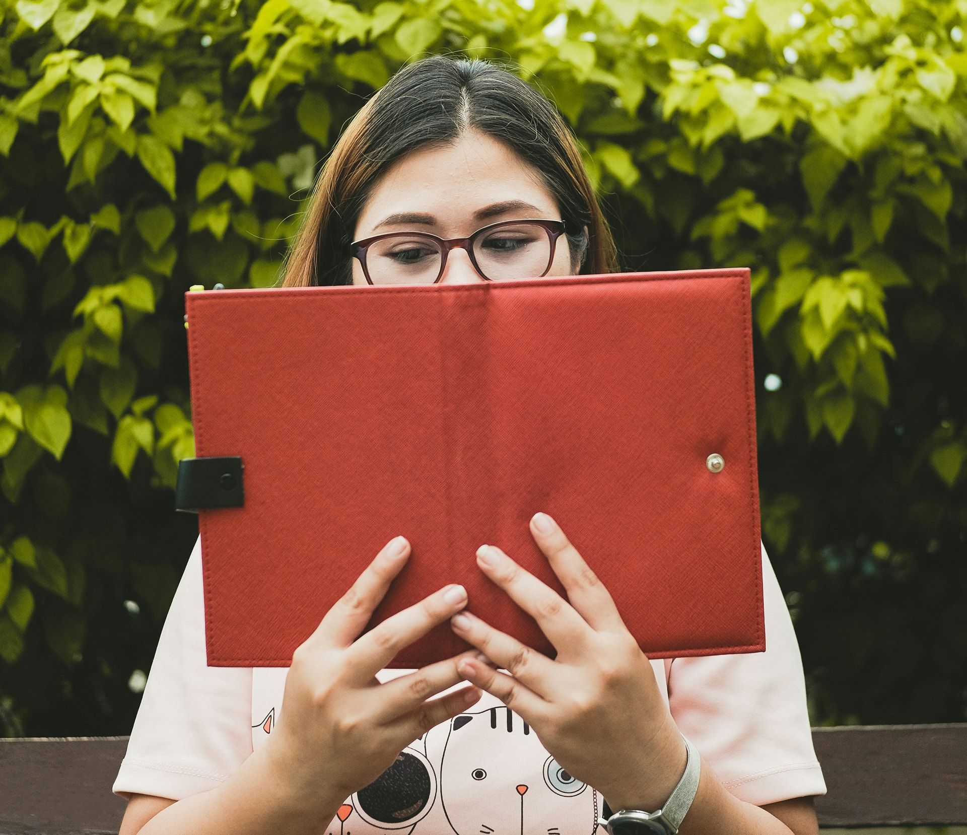 A woman wearing glasses is reading a book on a tablet