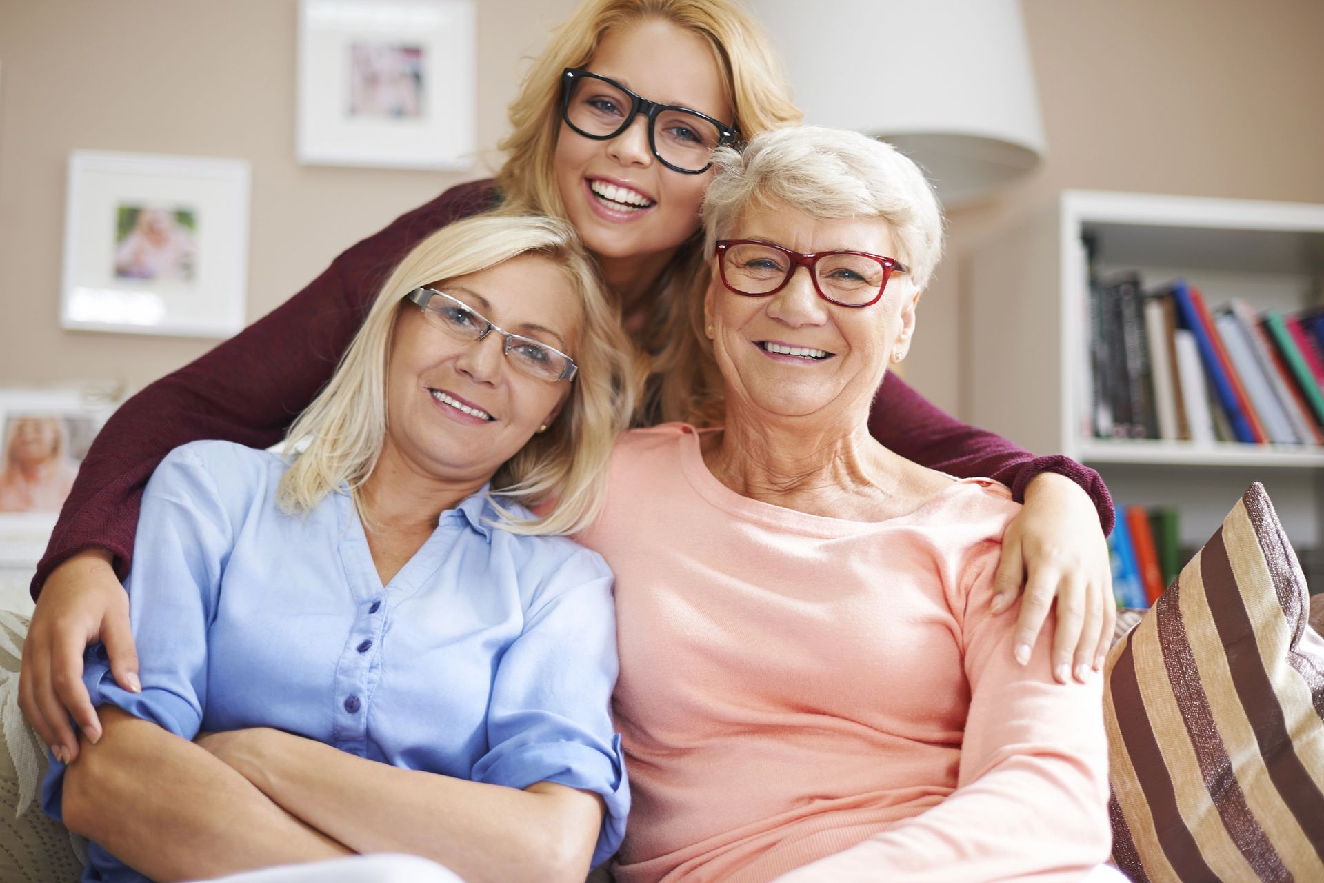 Three smiling women sitting together on a couch in a cozy living room
