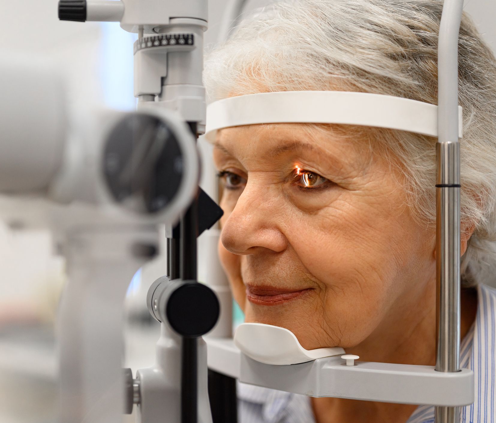 An eye examination with a patient resting their chin on a slit lamp headrest while a doctor examines their eye.