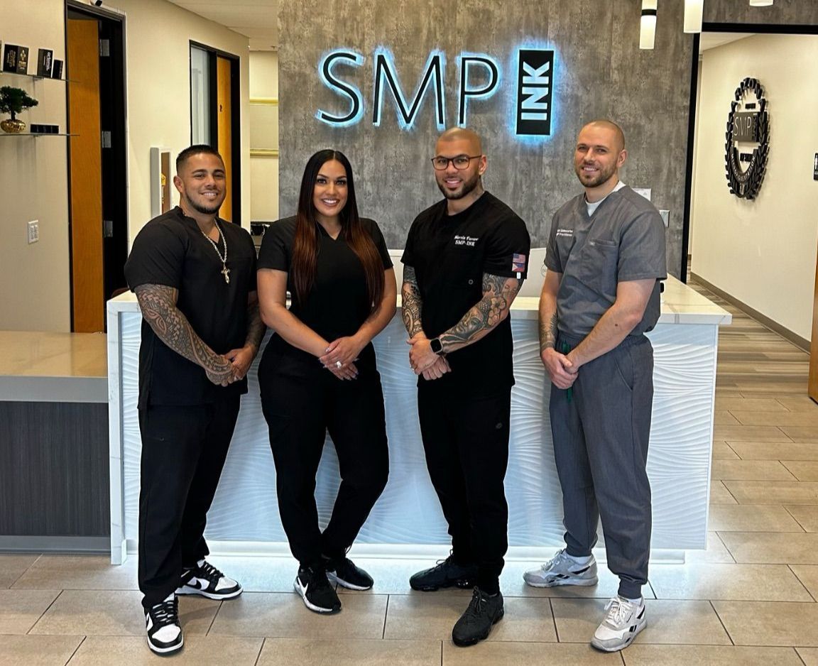 Four people posing in front of an SMP Ink reception desk in a bright office lobby