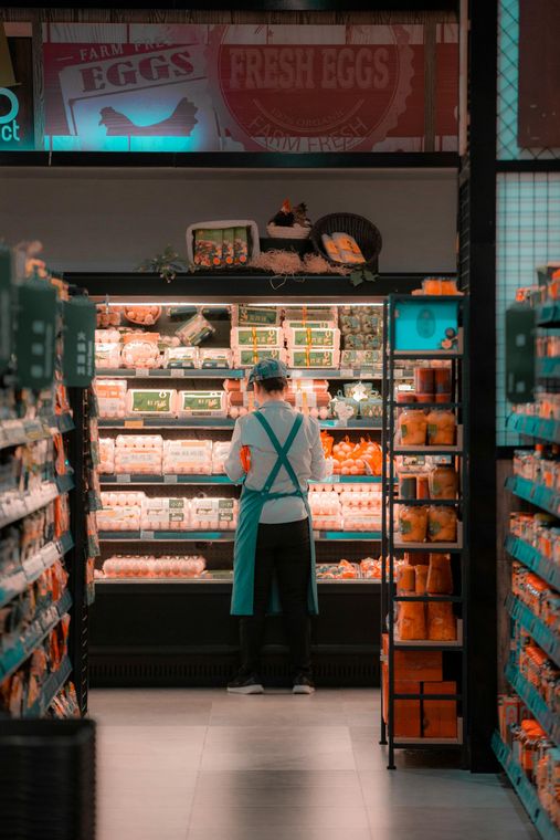 A man is standing in front of a refrigerator in a grocery store.