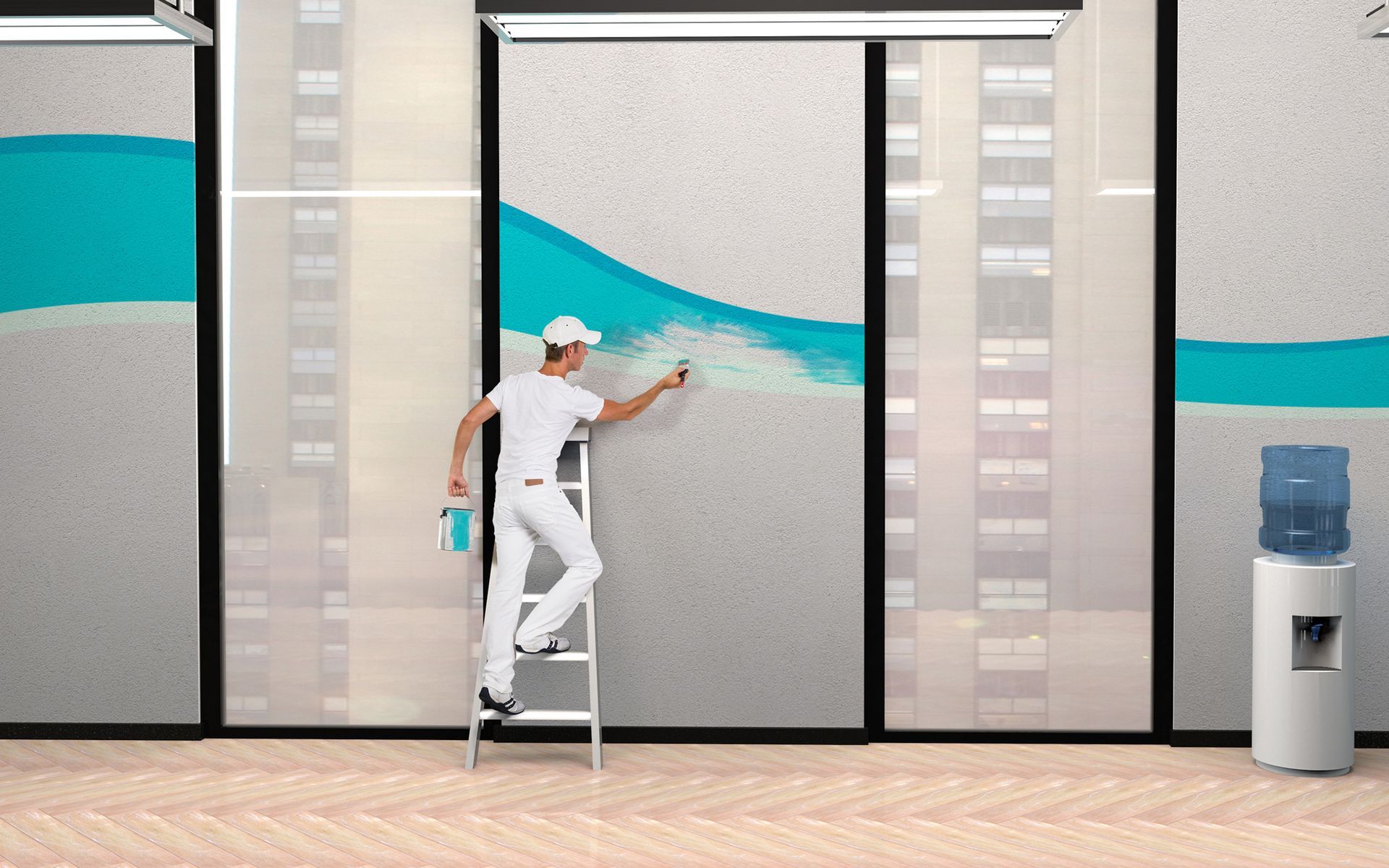 A man is standing on a ladder painting a wall.