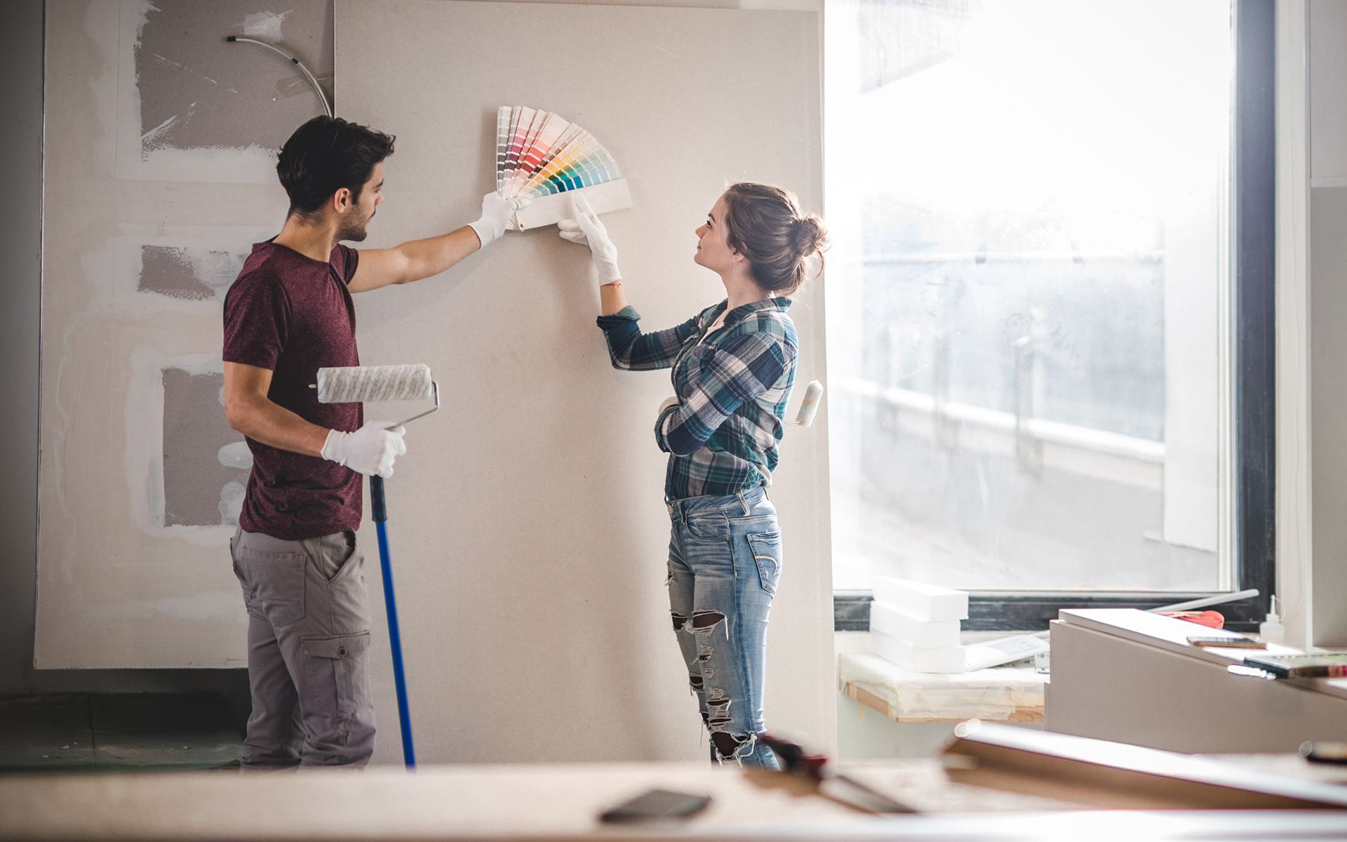 A man and a woman are painting a wall together.