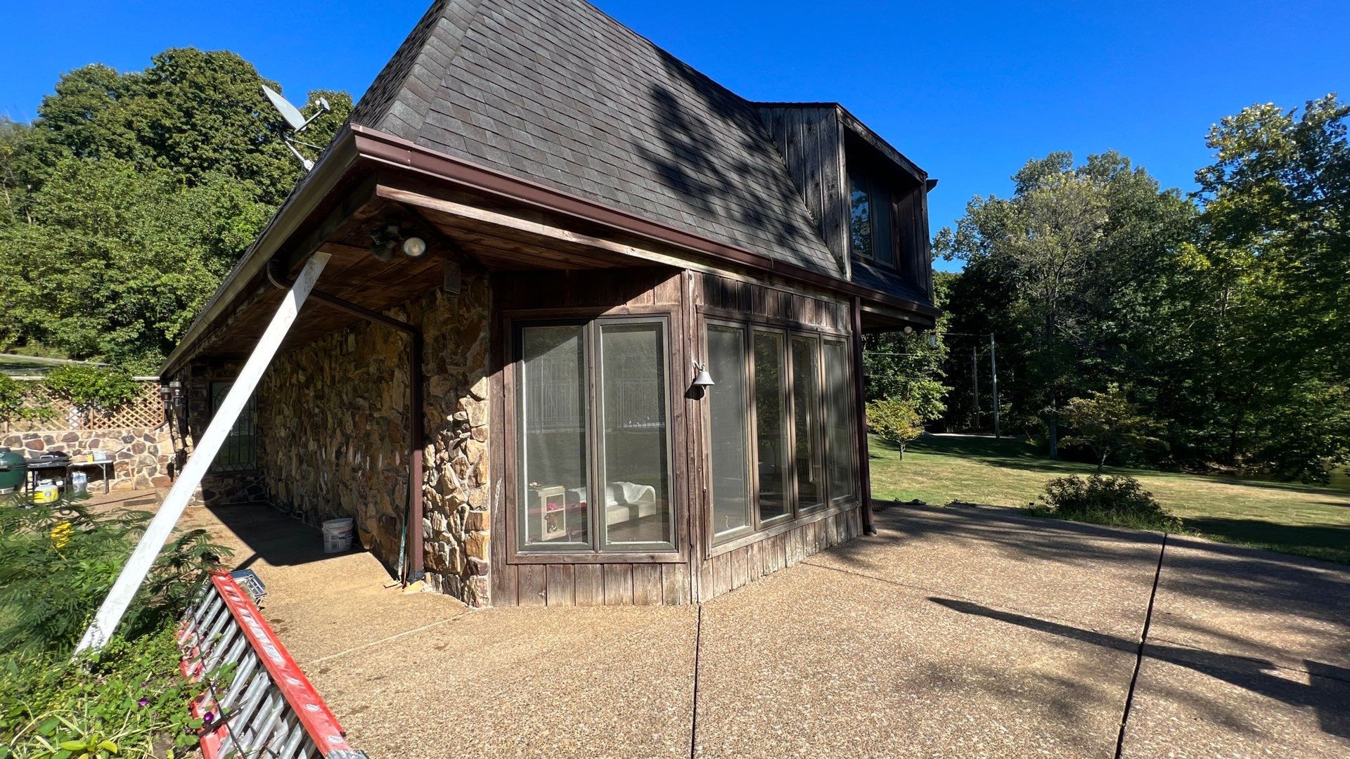 A small house with a lot of windows and a ladder in front of it.