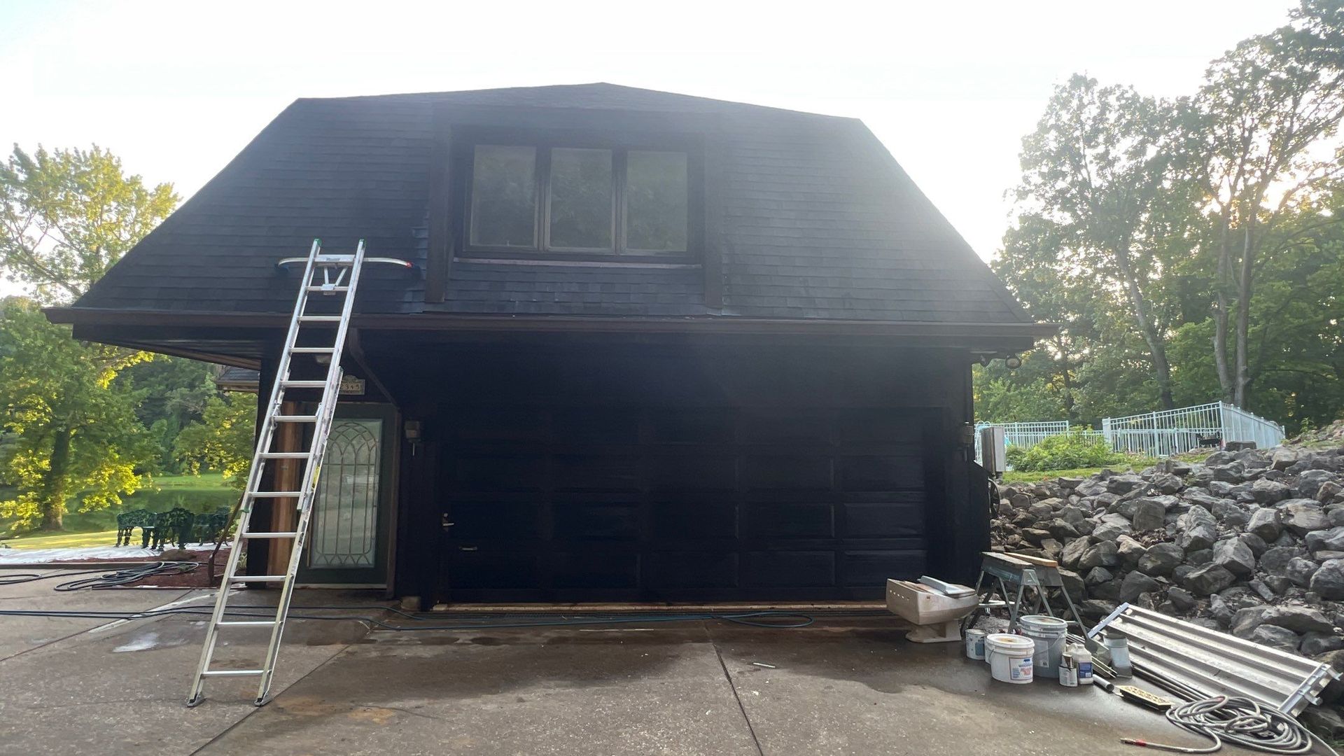 A ladder is sitting in front of a black garage door.
