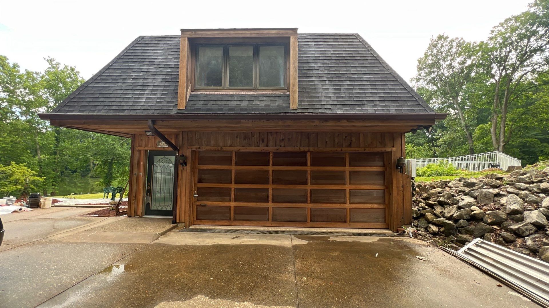A wooden garage with a black roof and a window