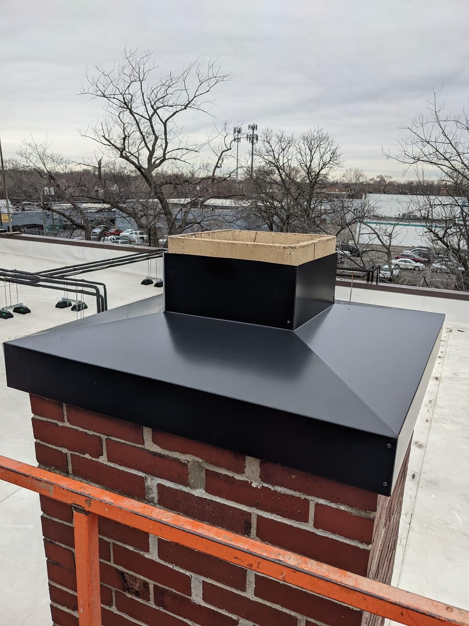 A brick chimney with a black metal cap on top of it.