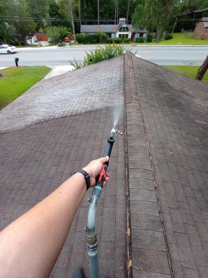 A person is using a hose to clean a roof.