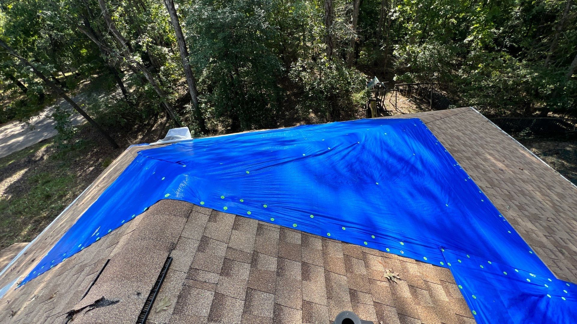 A blue tarp is covering the roof of a house.