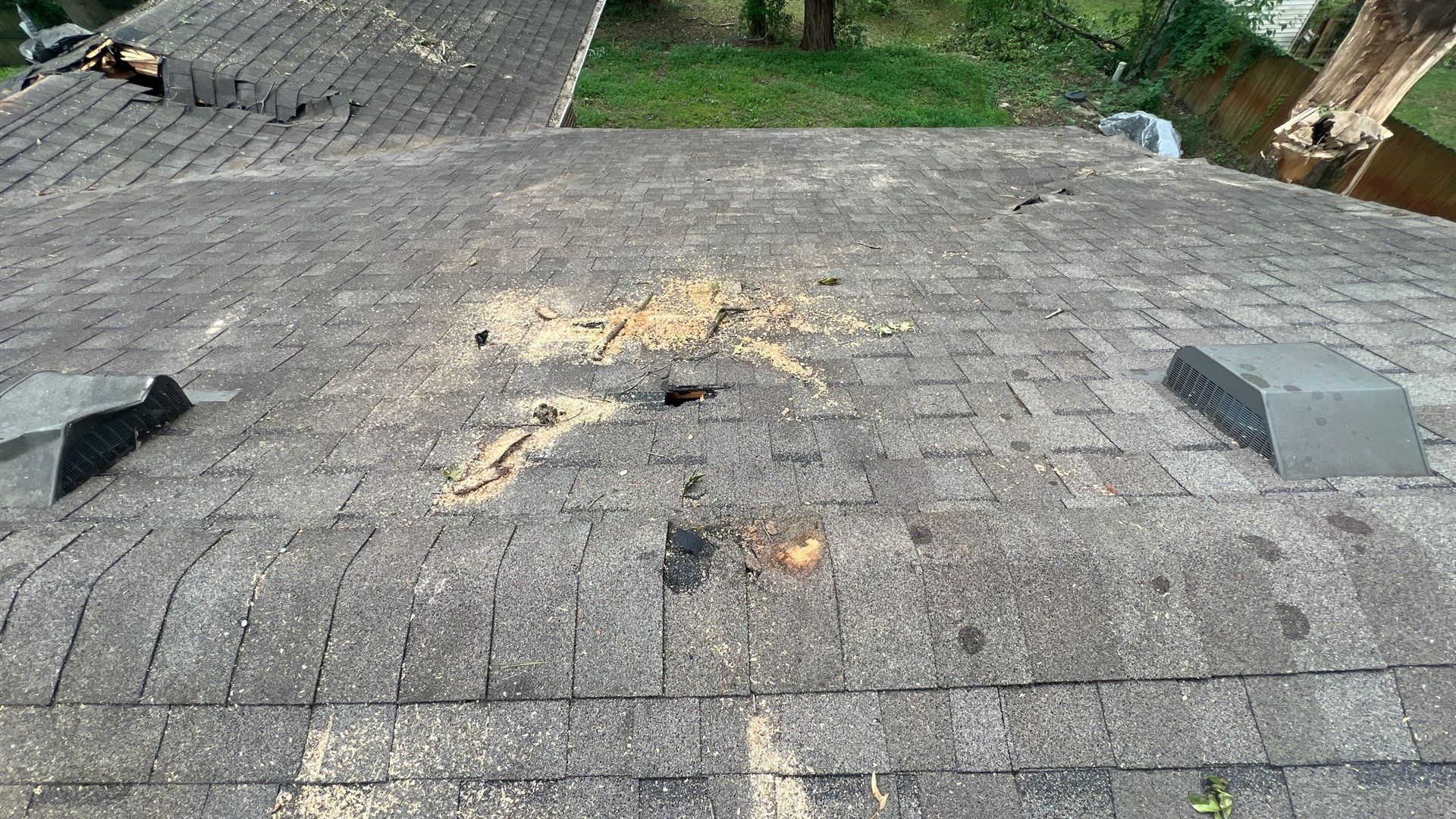 A roof with a hole in it and a few vents on it.