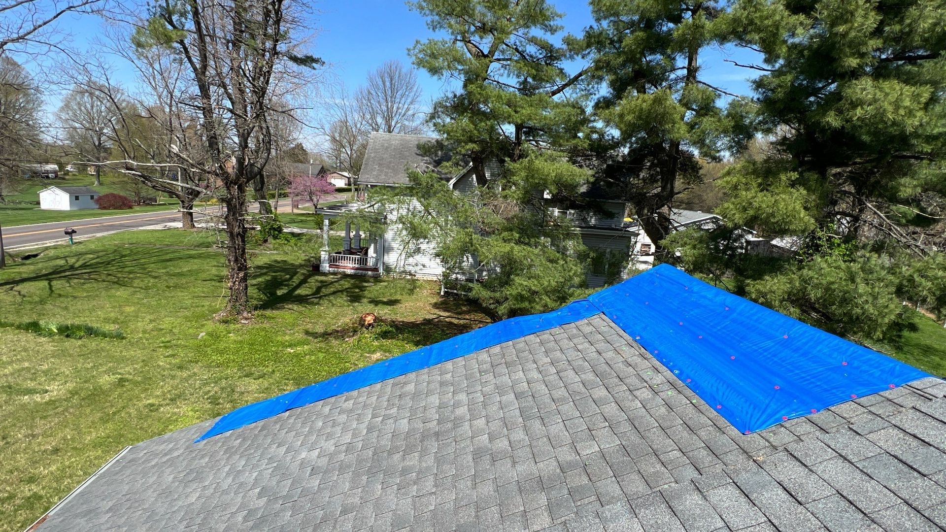 A blue tarp is covering the roof of a house.
