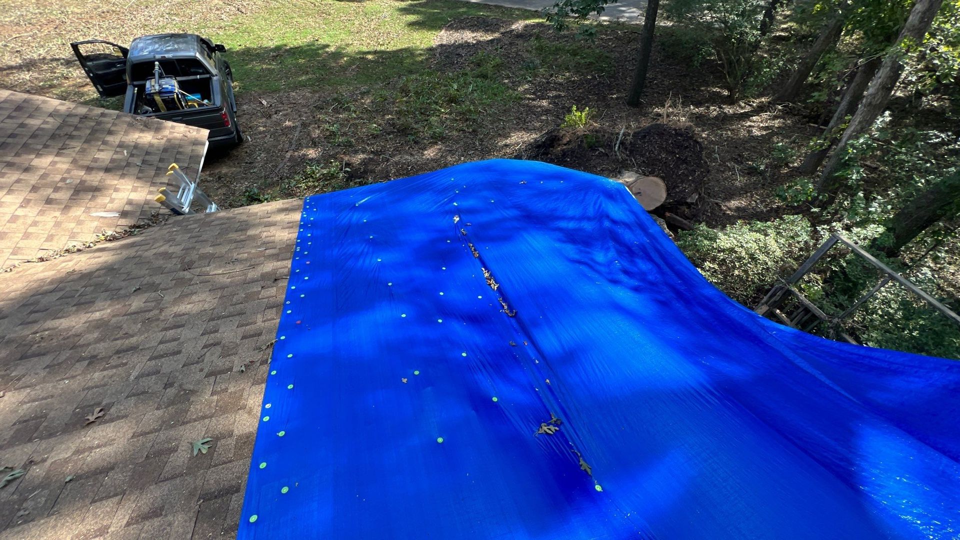 A blue tarp is sitting on top of a dirt field next to a truck.