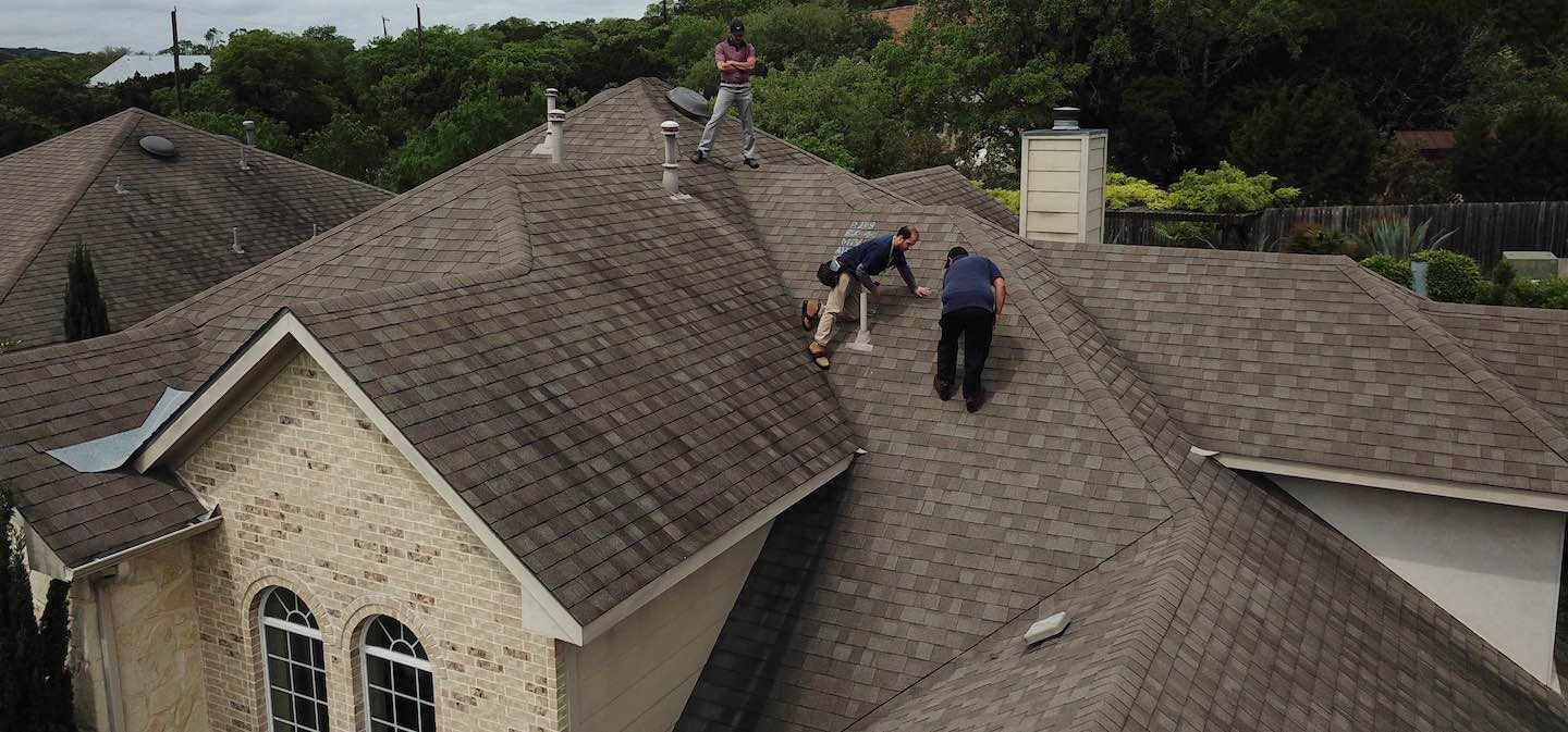 A group of men are working on the roof of a house.