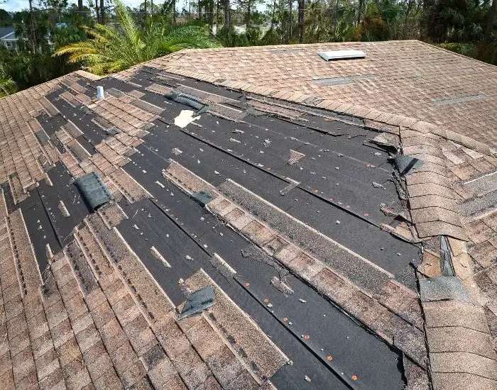 The roof of a house is missing shingles and is being repaired.