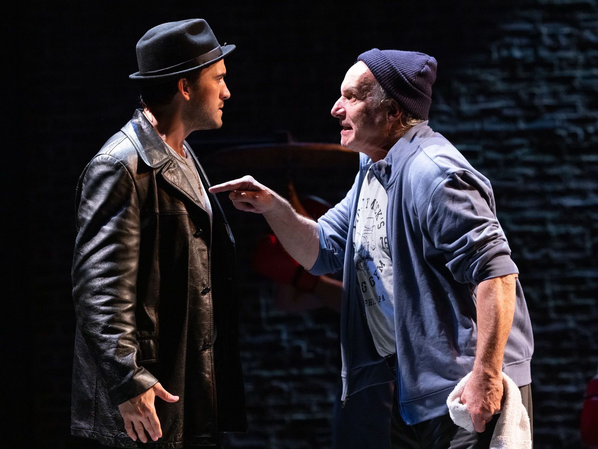 Two men are standing next to each other on a stage talking to each other.
