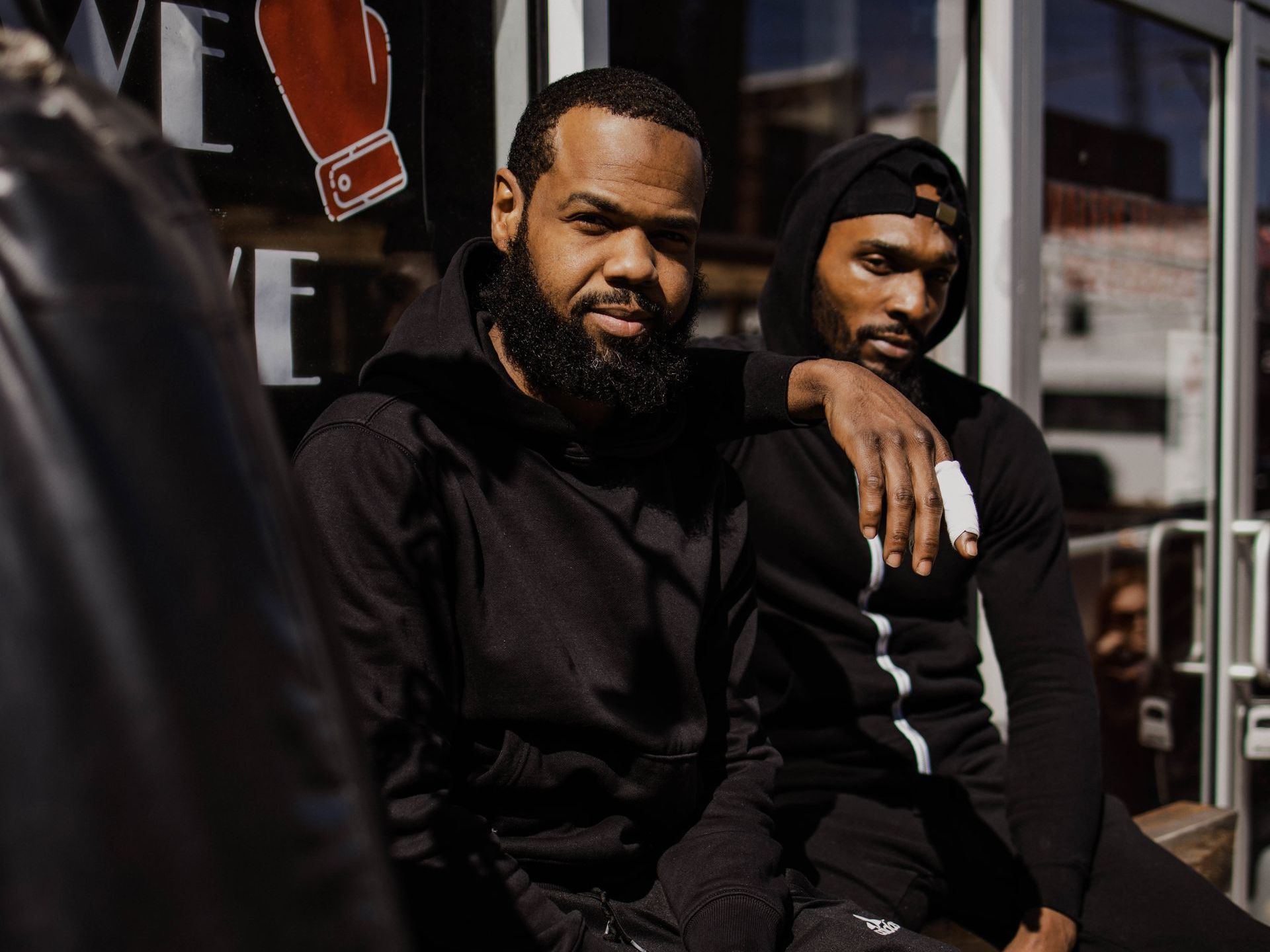 Two men are sitting next to each other in front of a building.