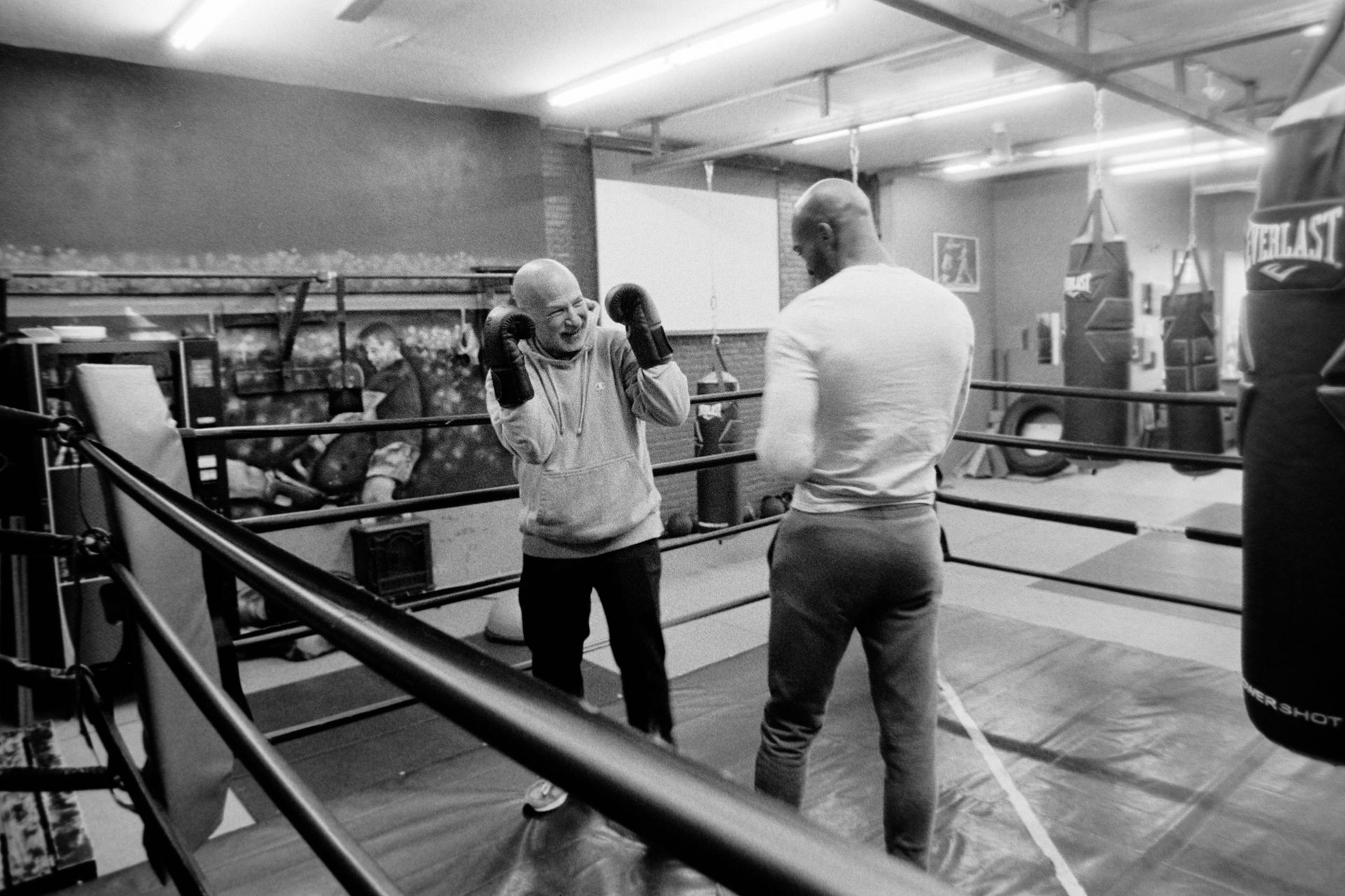 Two men are boxing in a boxing ring in a gym.