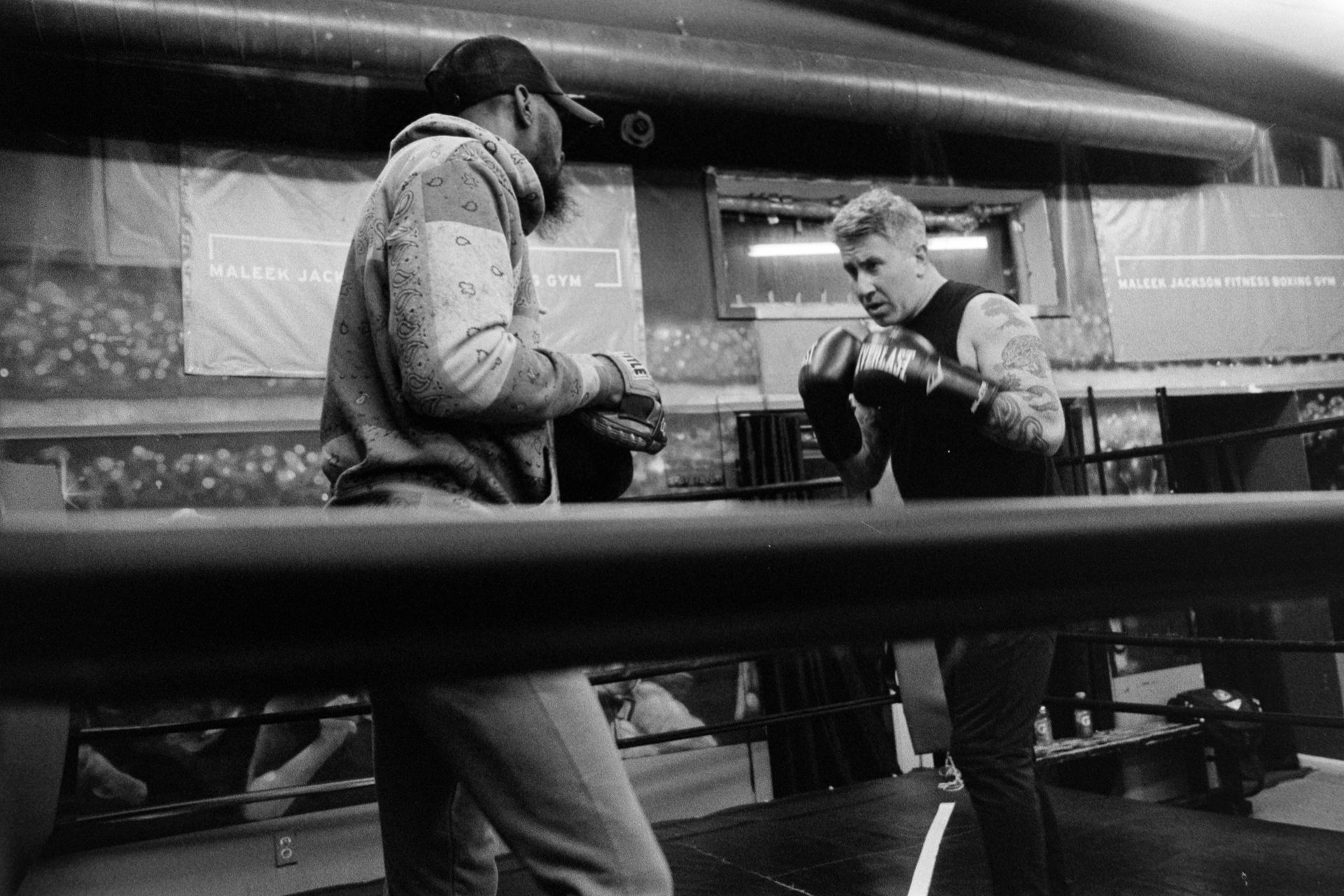 Two men are standing in a boxing ring talking to each other.