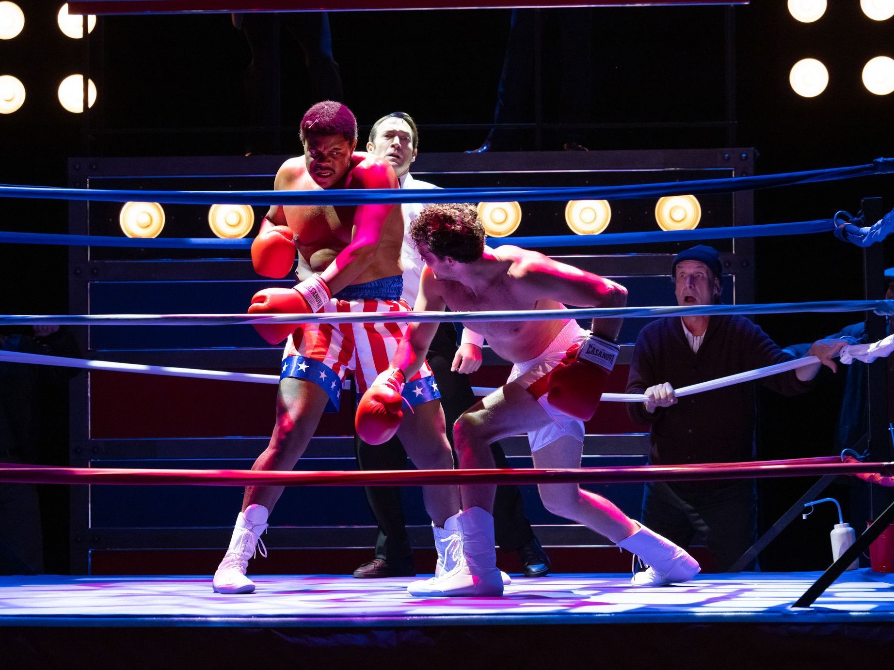 Two men are boxing in a ring with a referee watching.