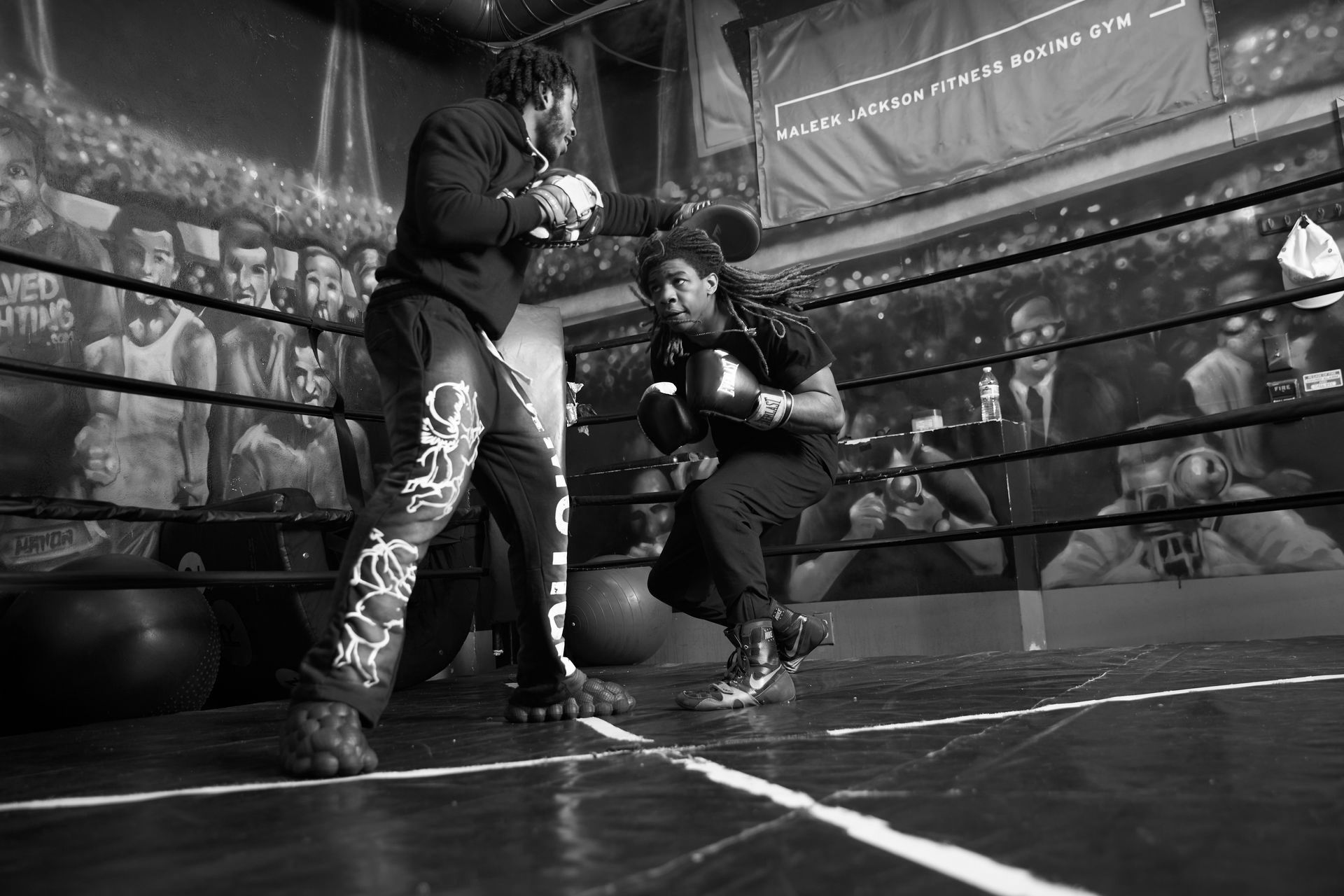 Two men are boxing in a boxing ring in a black and white photo.