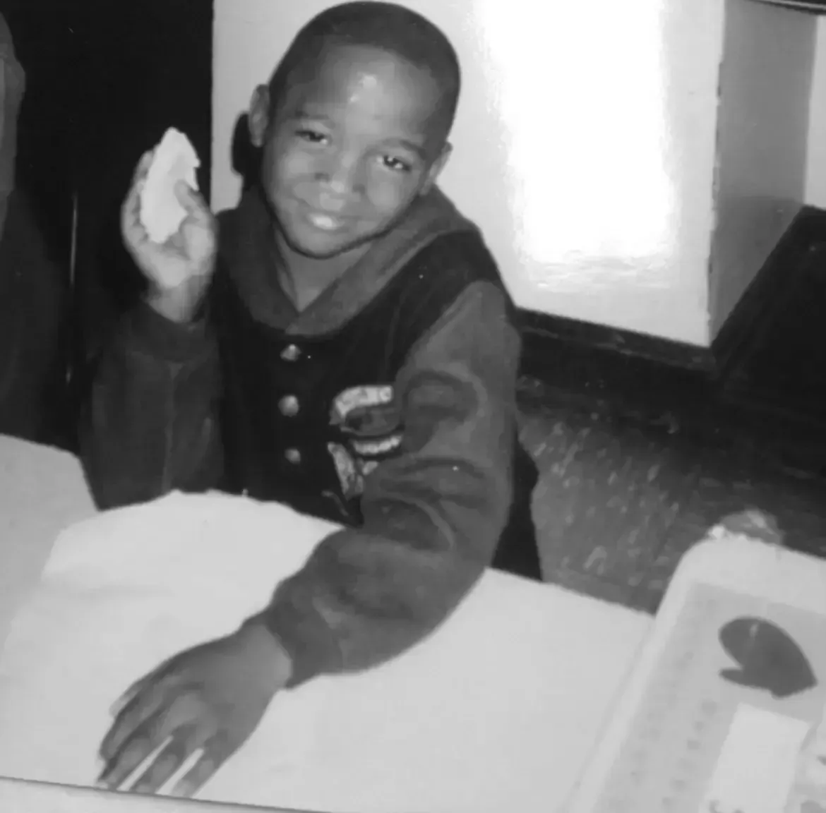 A black and white photo of a young boy holding a piece of paper
