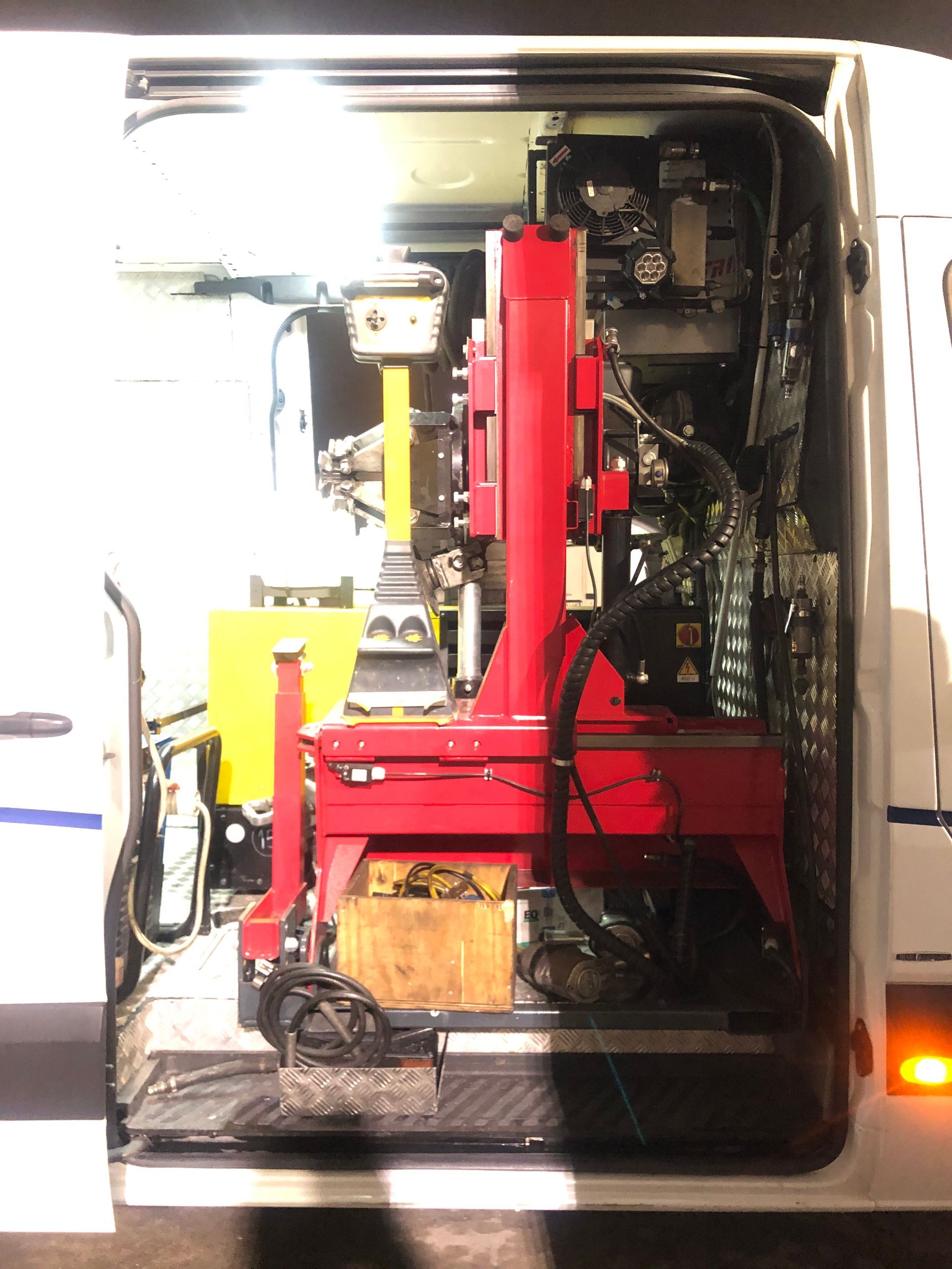 Interno di un furgone aperto con una macchina industriale rossa e vari componenti meccanici.