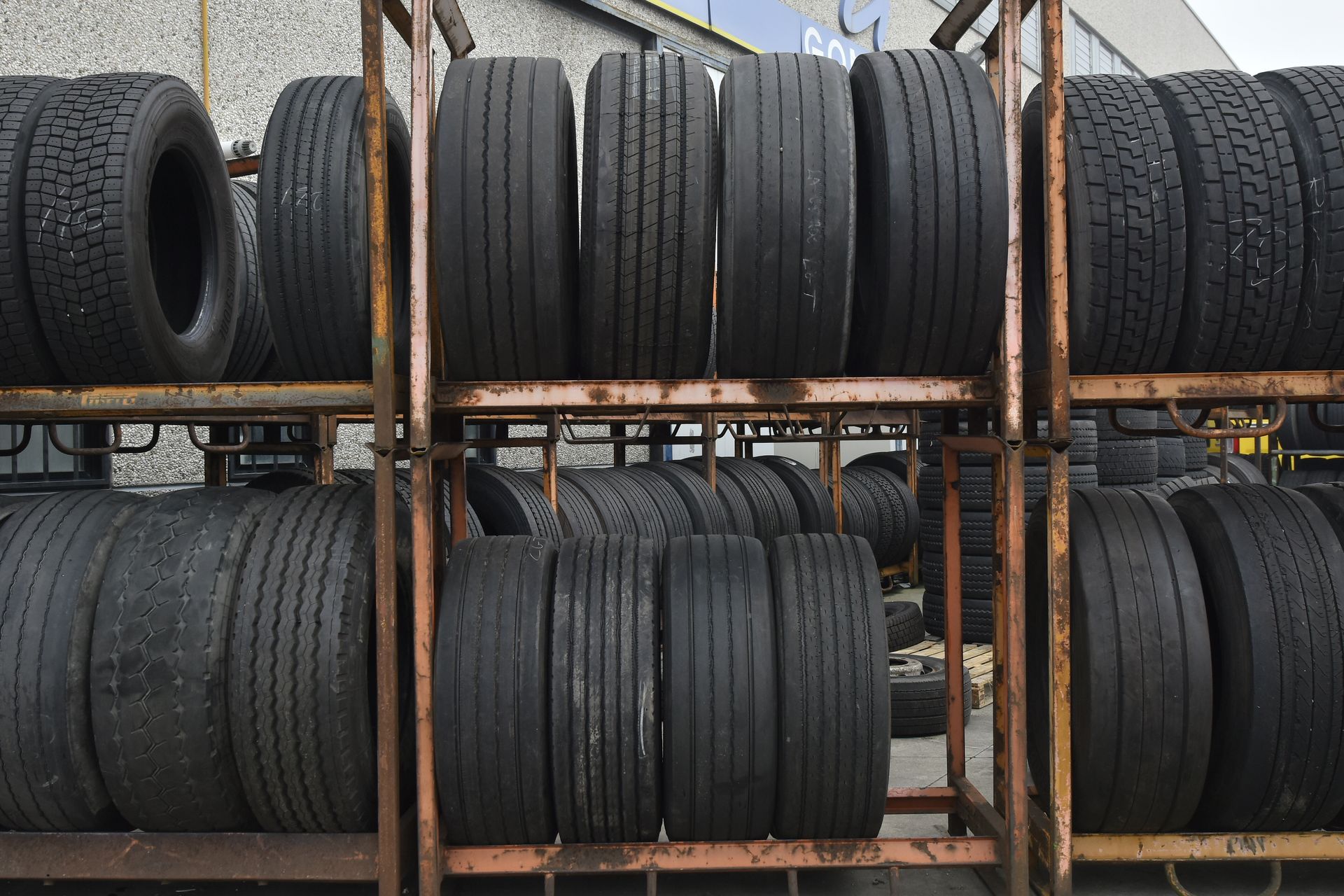 Pneumatici accatastati su scaffalature metalliche in un'area di stoccaggio all'aperto.