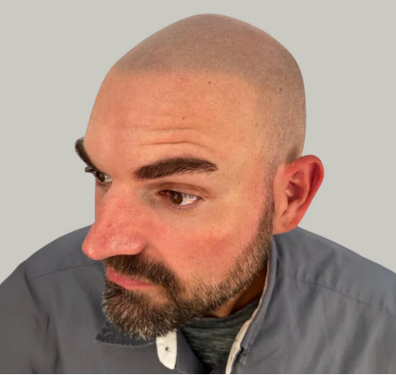 Side profile of a bald man with a beard wearing a gray jacket against a plain light background