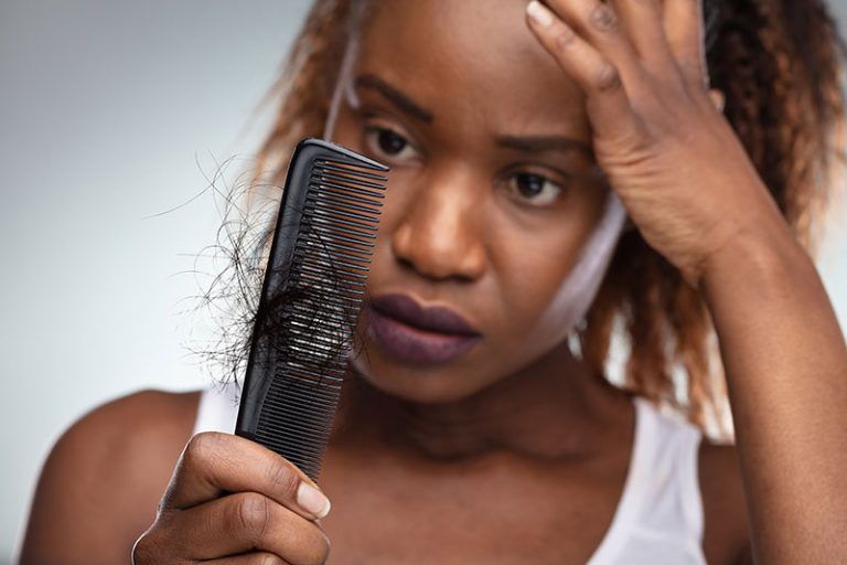 woman experiencing hair loss while combing her hair.