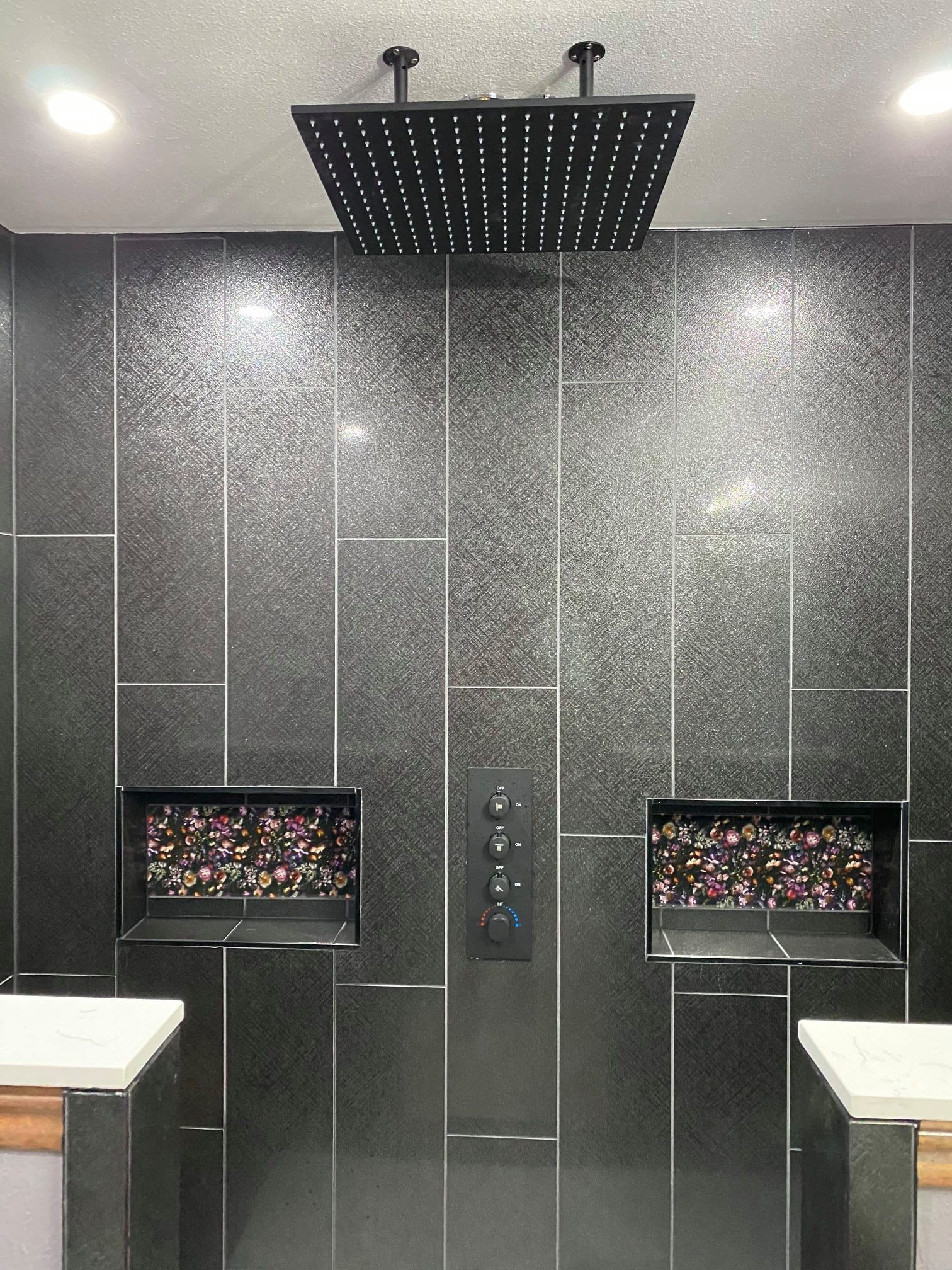 Modern elevator interior with dark textured walls, mirrored panels, and a ceiling rain shower fixture.