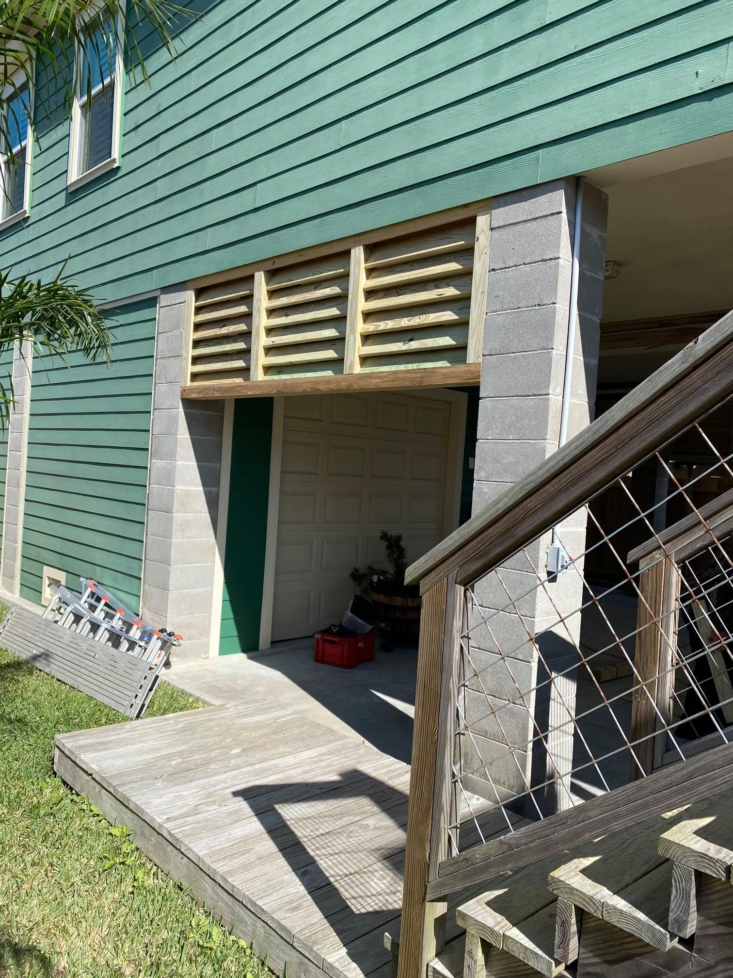 Backyard basement entrance with concrete steps, green siding, and a wooden railing beside a house