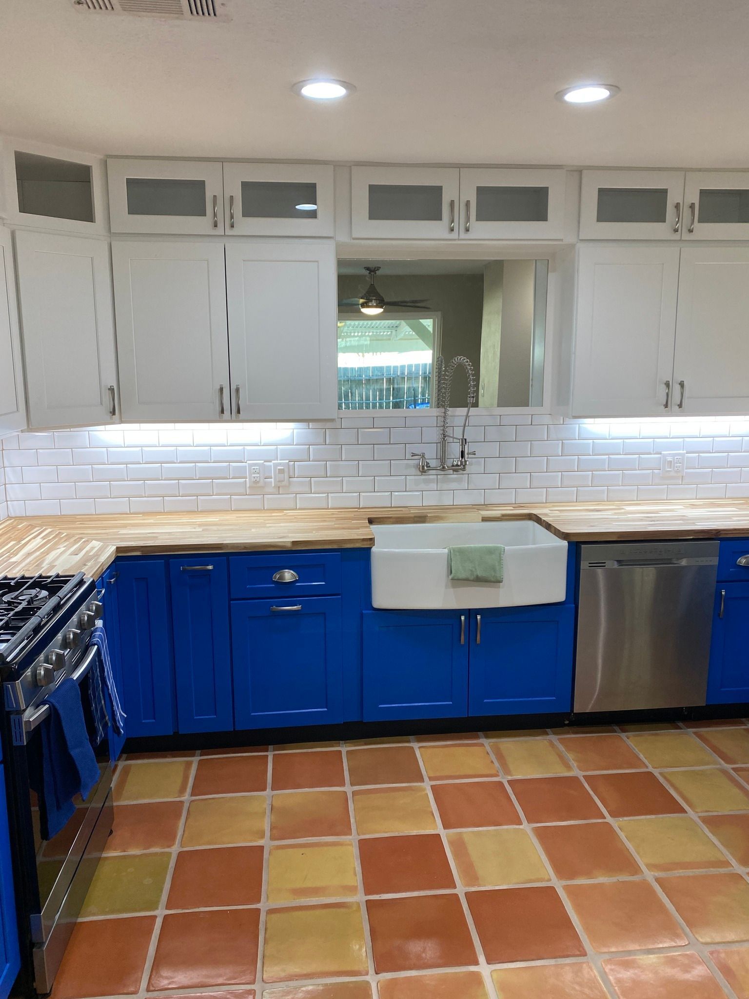 Blue and white kitchen with terracotta tile floor and stainless steel appliances