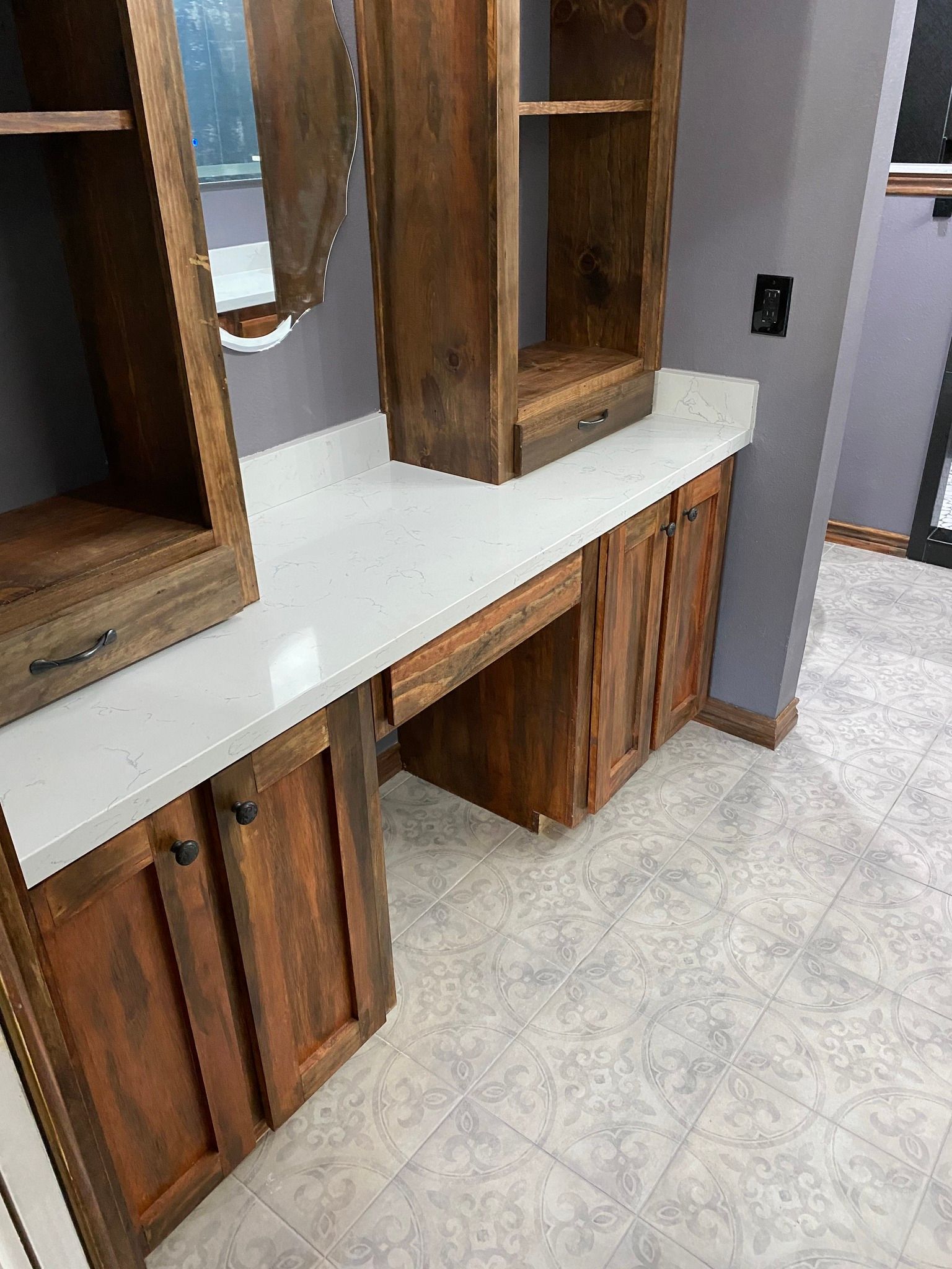 Bathroom vanity with wood cabinets, white countertop, and speckled tile floor