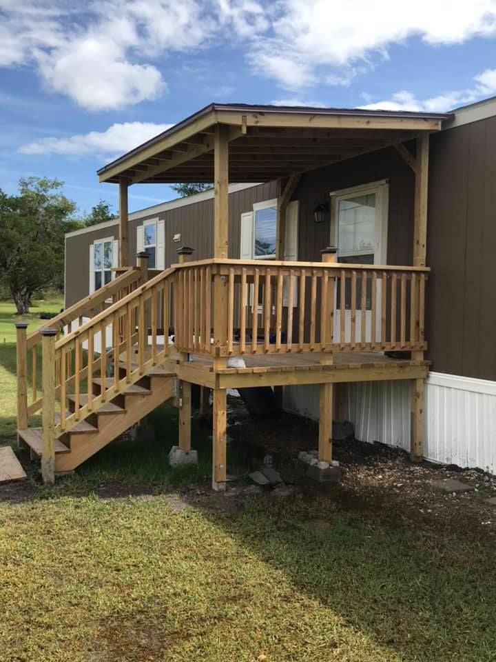 Wooden porch and stairs attached to a small tan house under a cloudy sky