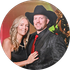 Smiling couple dressed in black and red, posing in front of a festive autumn backdrop