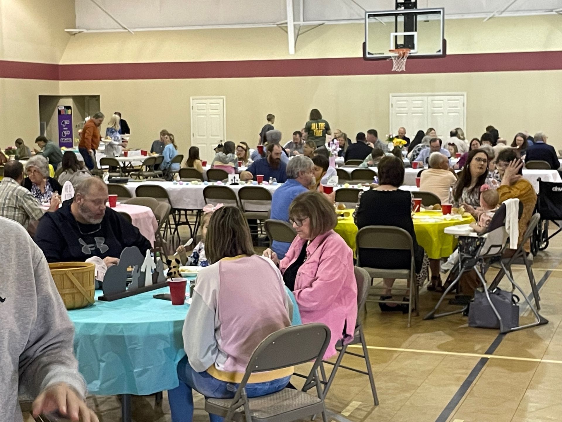 A large group of people are sitting at tables in a gym.