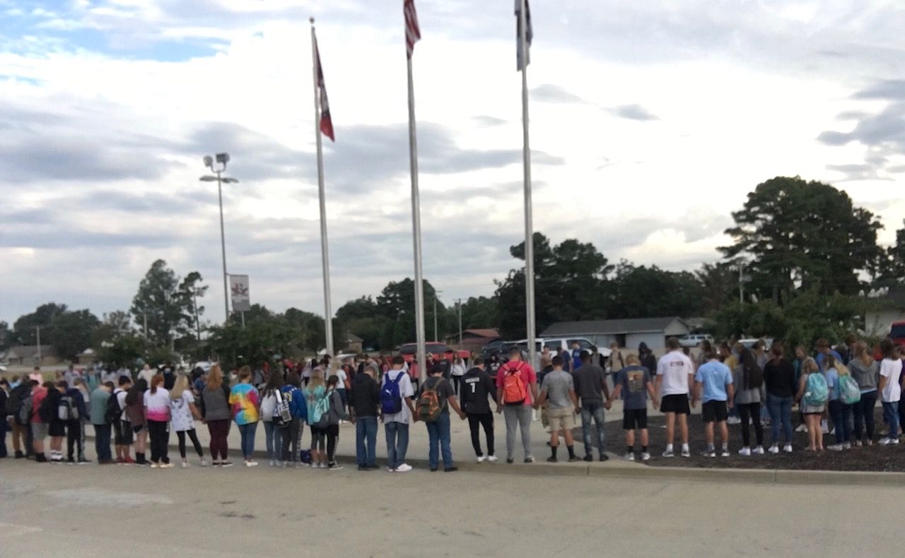 A group of people standing in front of a flag pole