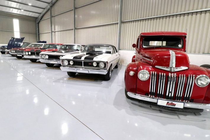 A row of old cars are parked in a garage.