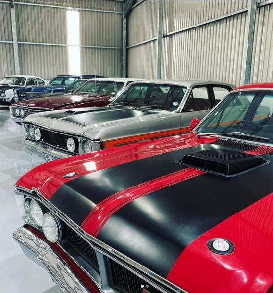 A row of classic cars are parked in a garage
