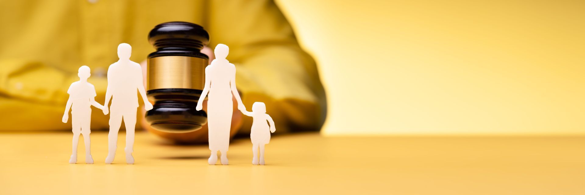 Miniature people standing near a gavel on a gold background, suggesting law or justice