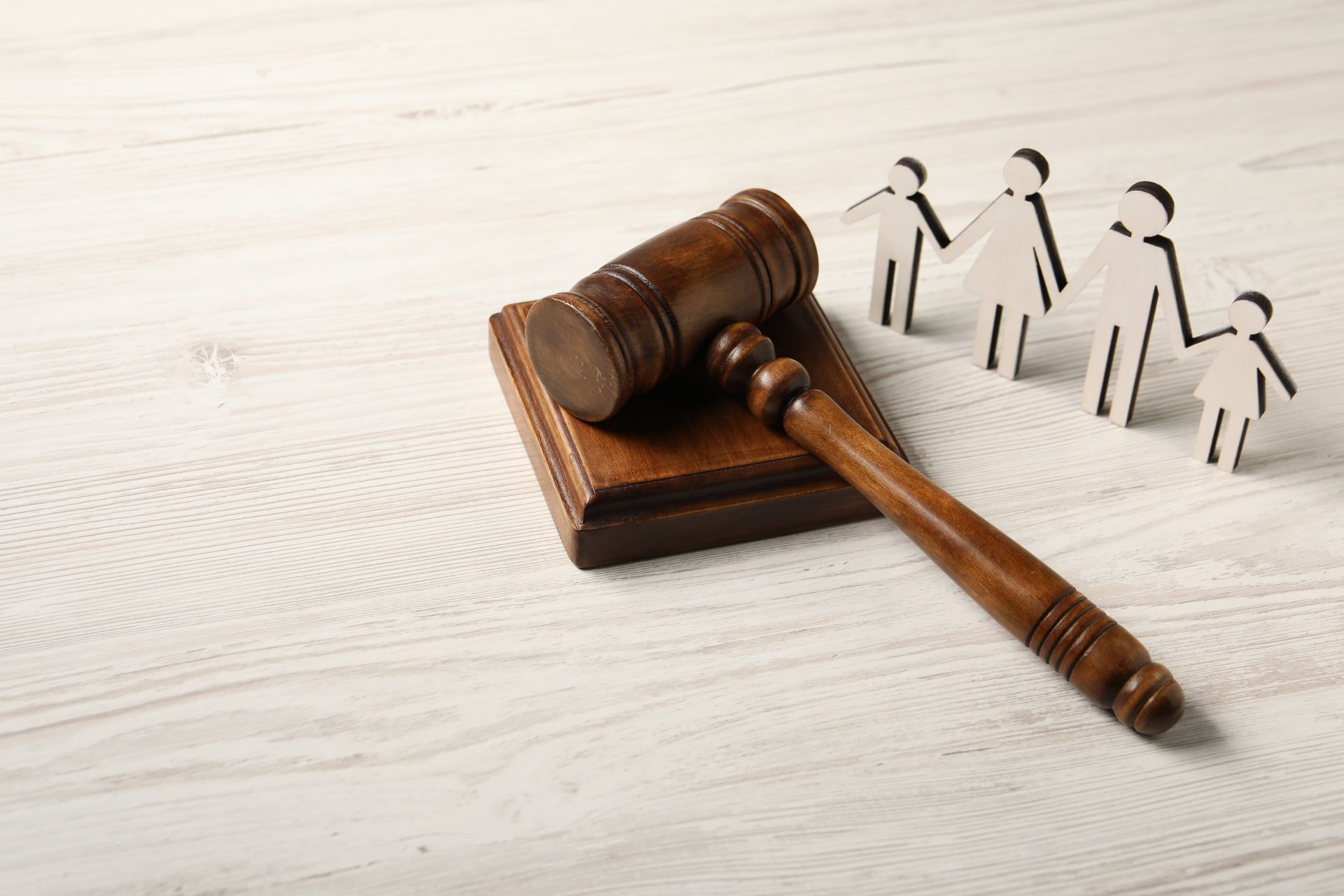 Wooden gavel beside small paper figures on a light surface