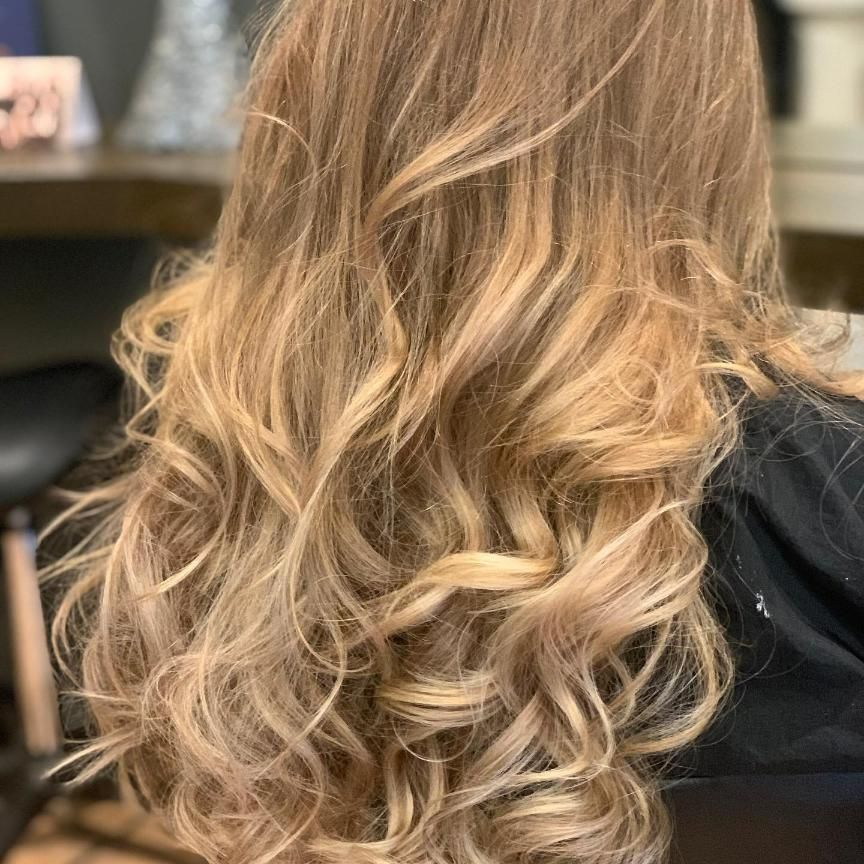 A Woman With Long Blonde Curly Hair is Sitting in a Chair — Energy Hair Co in Noosa Heads, QLD