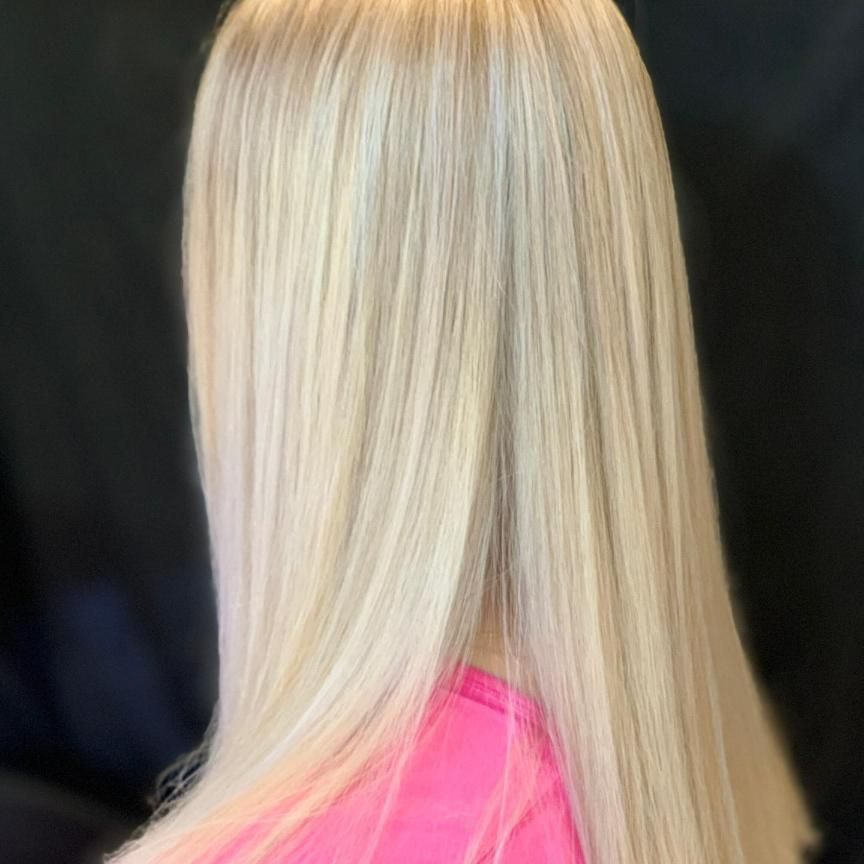 A Woman With Long Blonde Hair is Wearing a Pink Shirt — Energy Hair Co in Noosa Heads, QLD