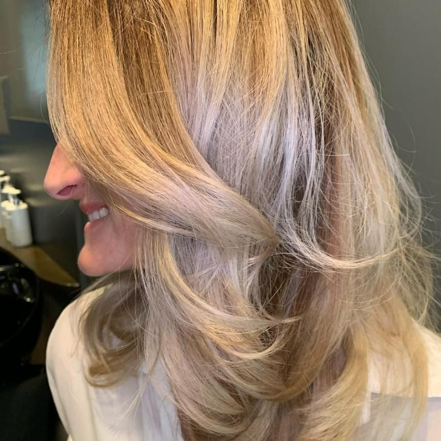 A Woman With Long Blonde Hair is Smiling and Wearing a White Shirt — Energy Hair Co in Noosa Heads, QLD