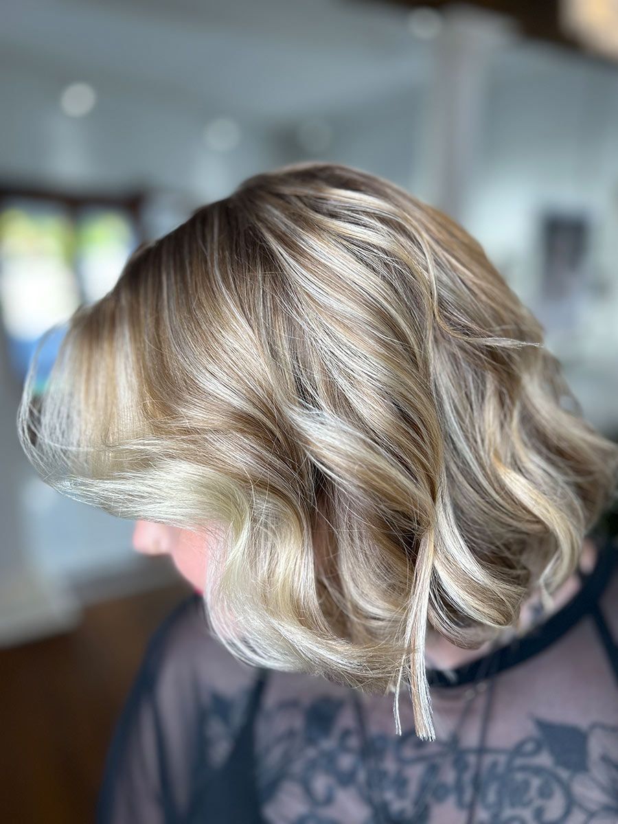 A Woman With Blonde Hair is Wearing a Black Shirt— Energy Hair Co in Sunshine Coast, QLD