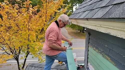 A man is kneeling on the roof of a house