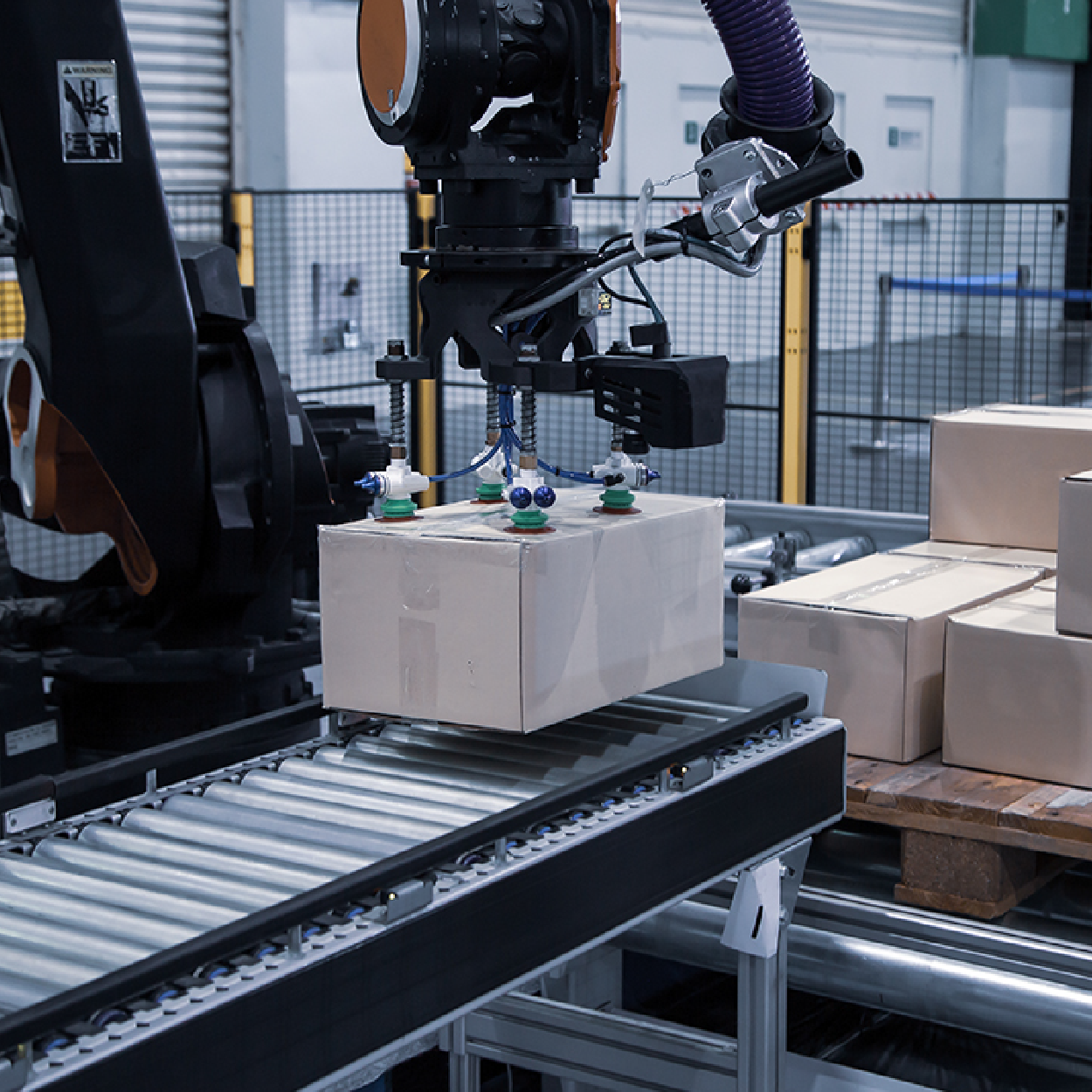 Industrial robot arm moving boxes on a factory conveyor belt